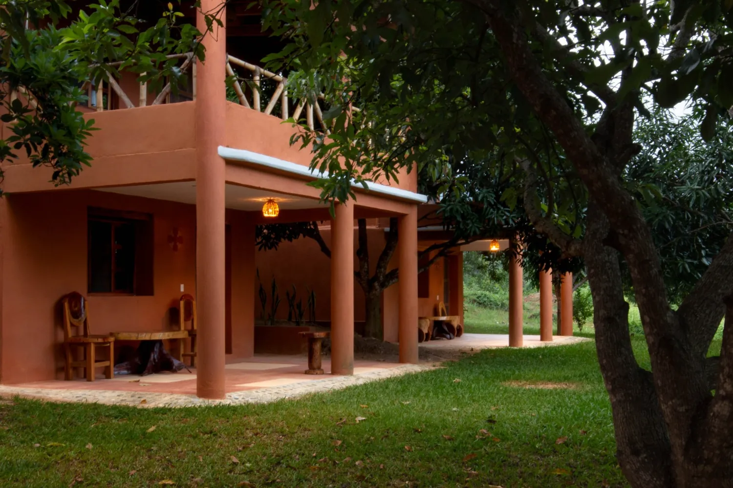 Cabañas de barro al atardecer con luces encendidas entre los mangos