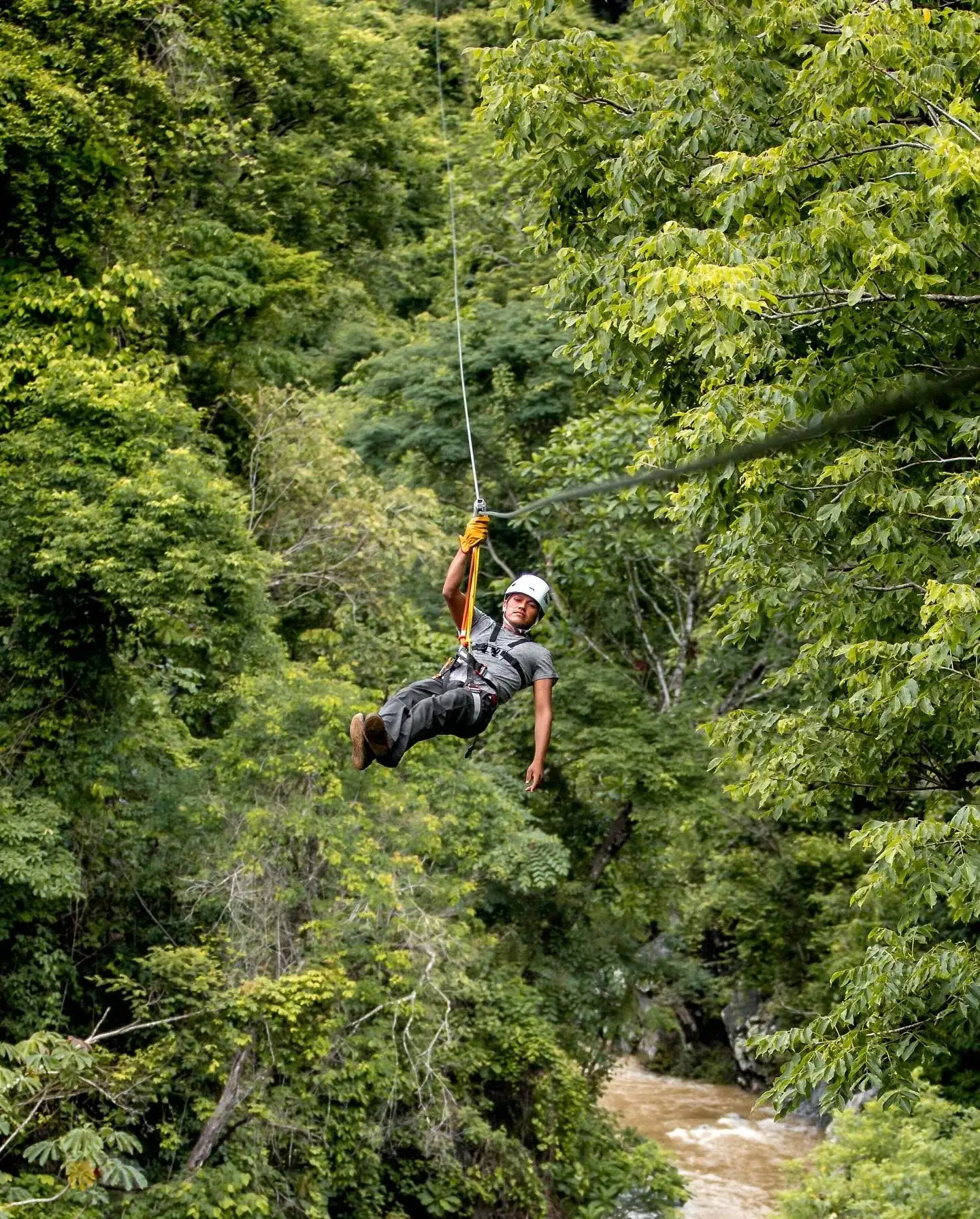 Persona cruzando en tirolesa sobre la selva y el río