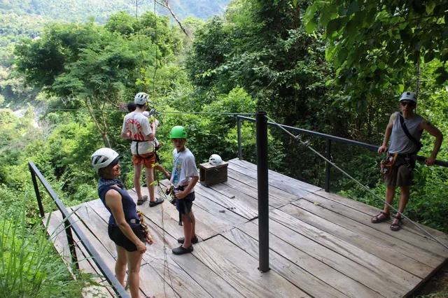 Familia con cascos en la plataforma de una tirolesa