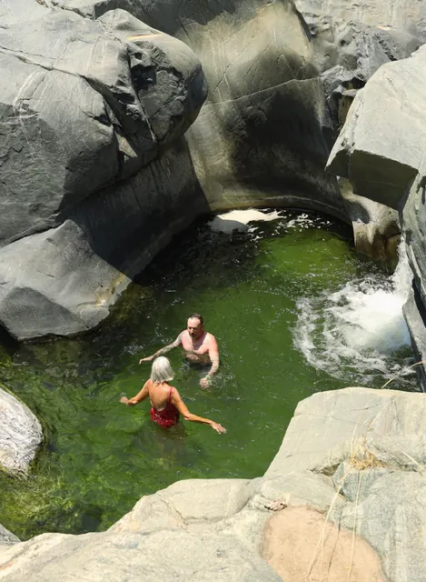 Visitantes nadando en la poza de la cascada