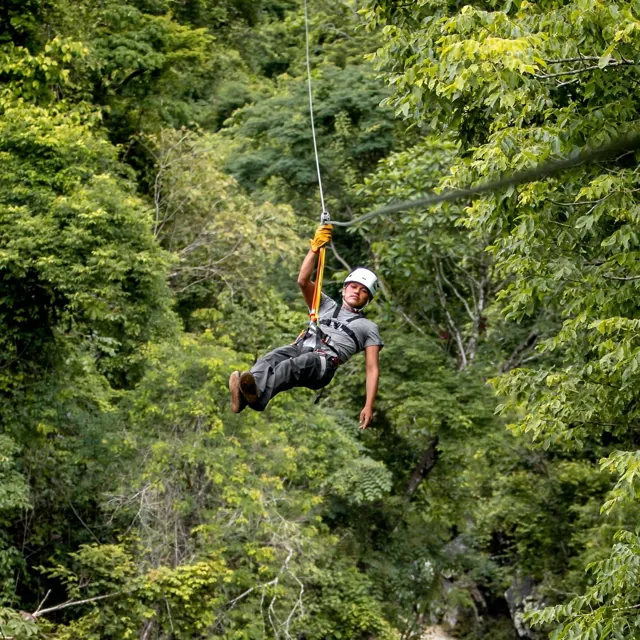 Persona en el aire sobre la selva en el circuito de tirolesas