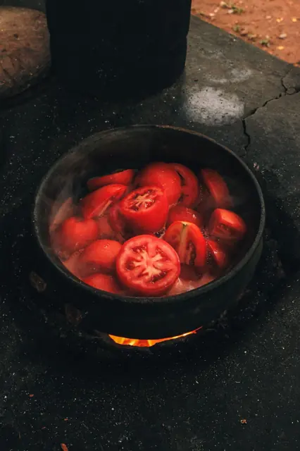 Tomates hirviendo en una olla de barro sobre el fogón